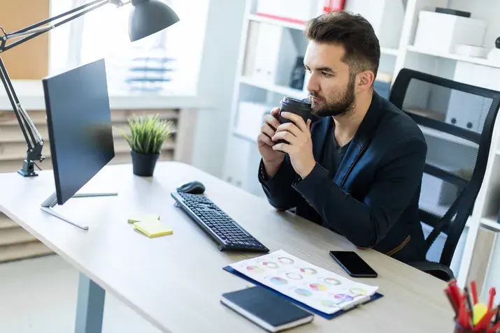 Businessman working at modern office desk with coffee