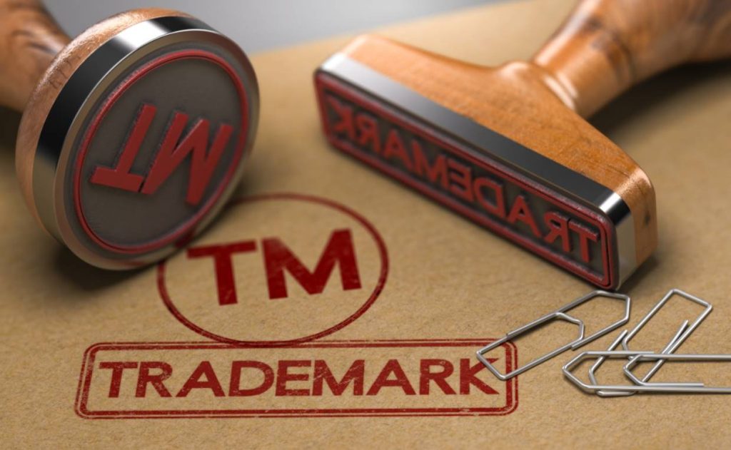 Close-up of a rubber stamp creating a red trademark logo on paper.