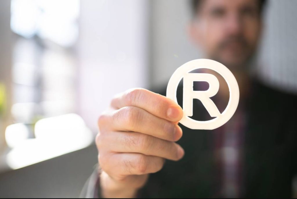 A man holding a white 3D registered trademark symbol.
