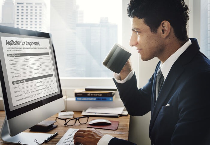Business professional completing an online application form on a desktop computer.