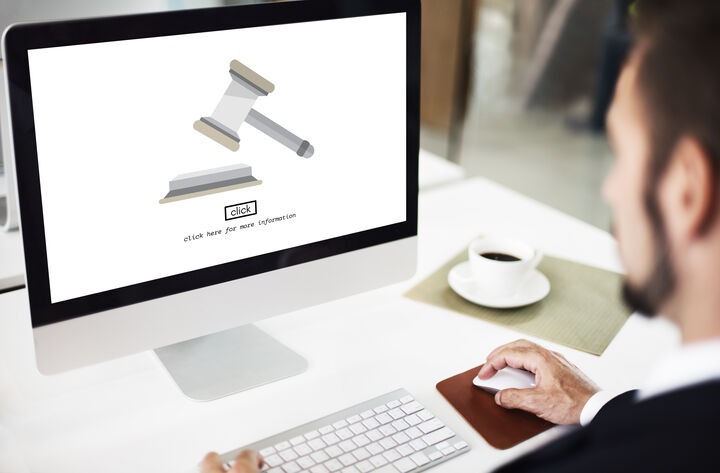 Person viewing a digital legal services screen with a gavel icon on a computer.